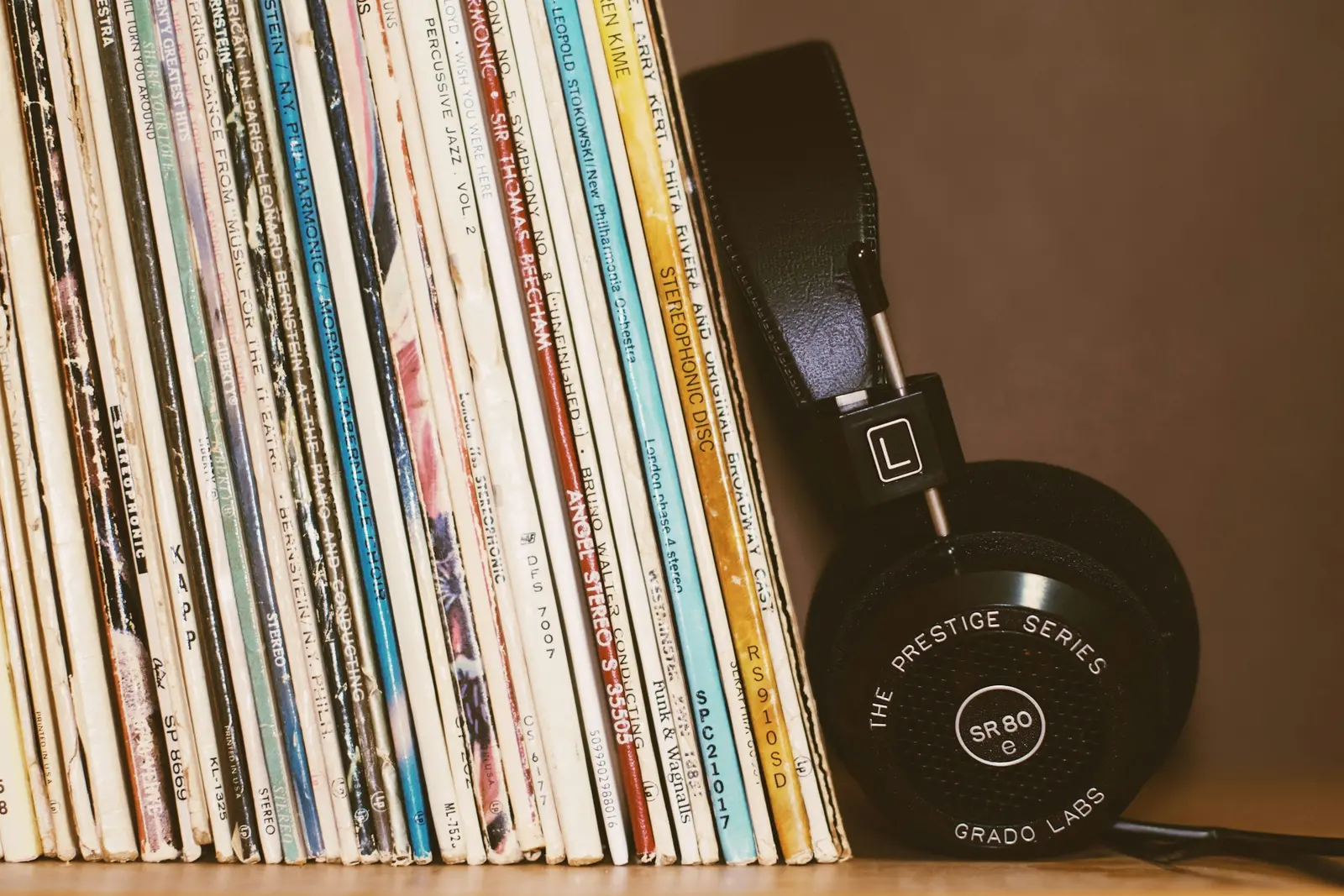 A shelf of vinyl records next to studio headphones